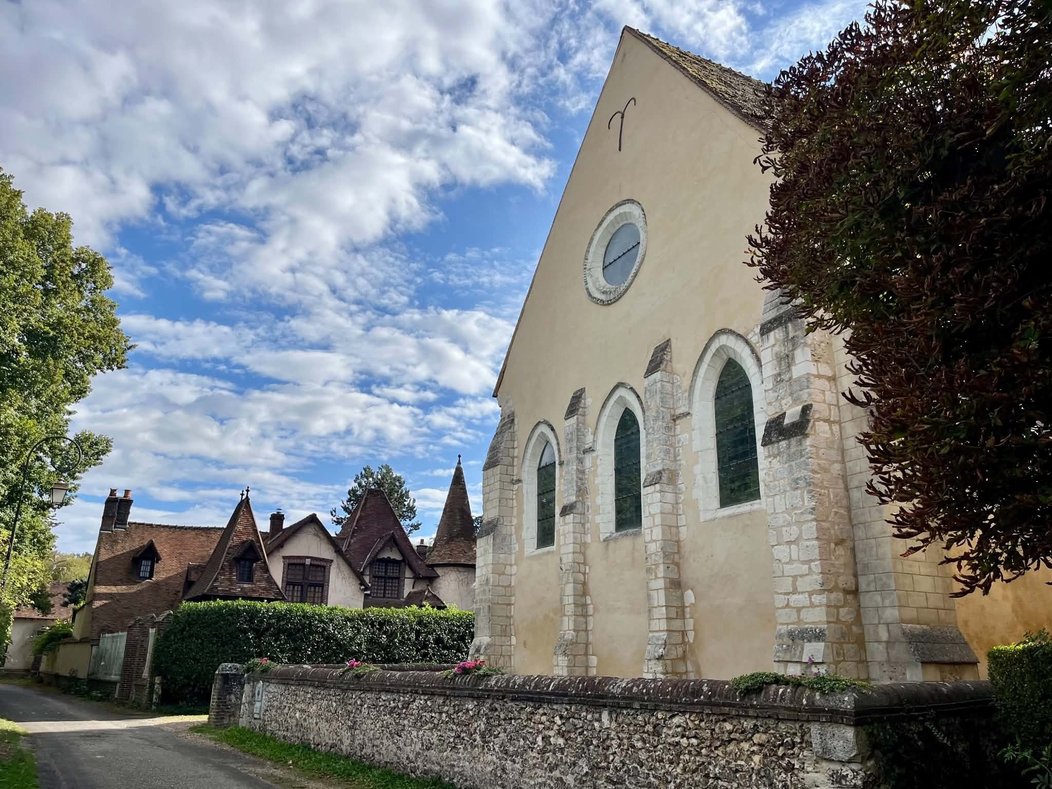 L’église Saint-Jean-Baptiste de Muzy vue depuis la rue du village, bordée de maisons normandes