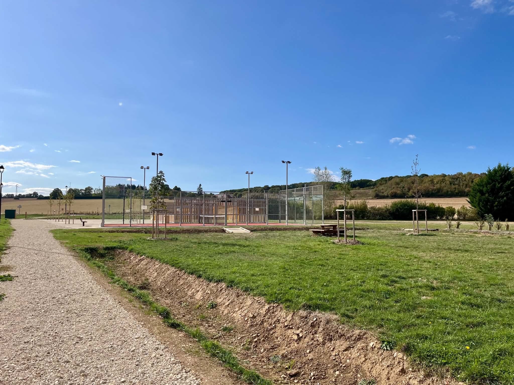 L’allée du parc de Muzy engazonnée, menant au terrain de padel