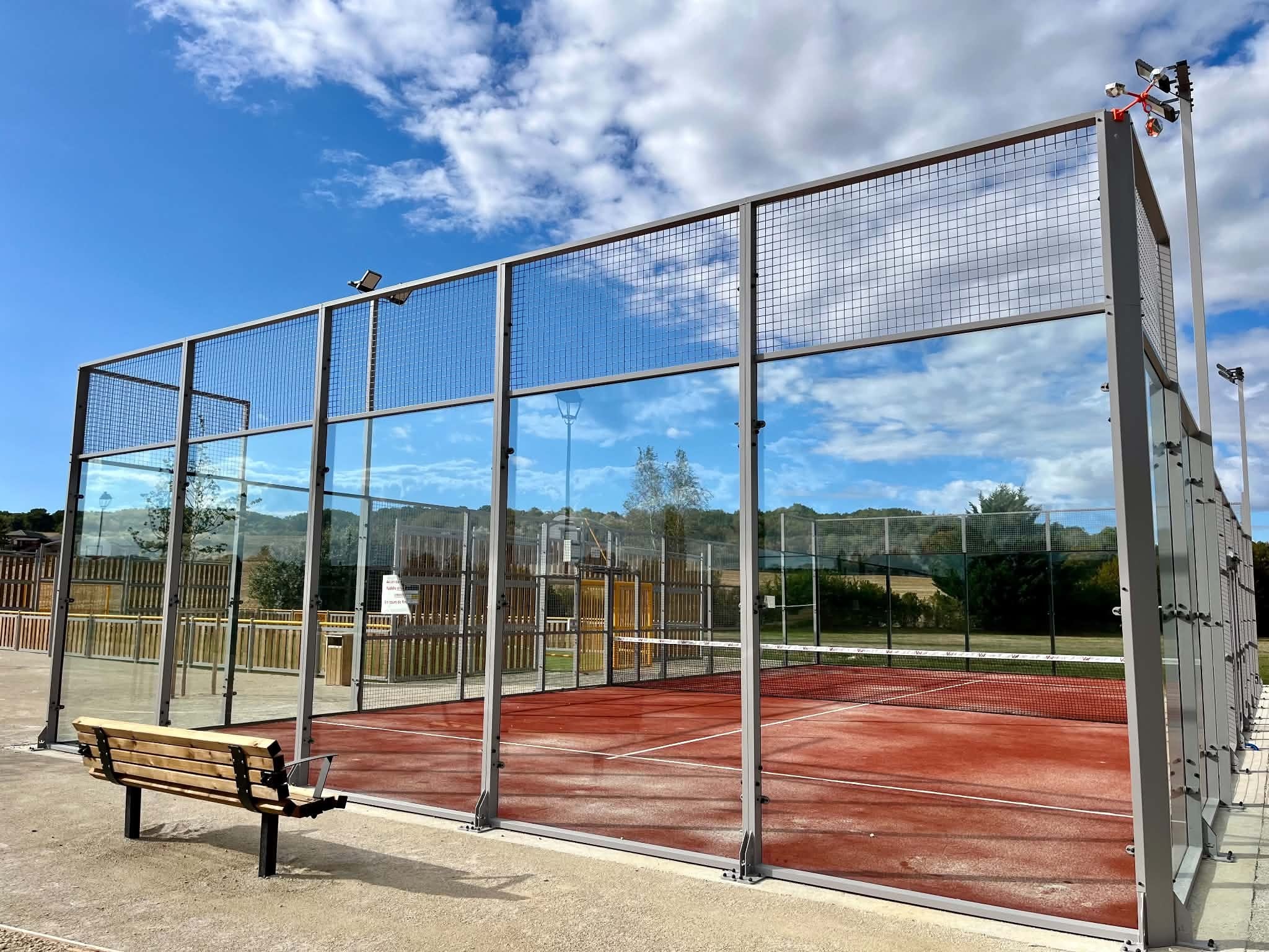 Le court de padel de Muzy terminé : revêtement rouge, parois vitrées et banc de touche